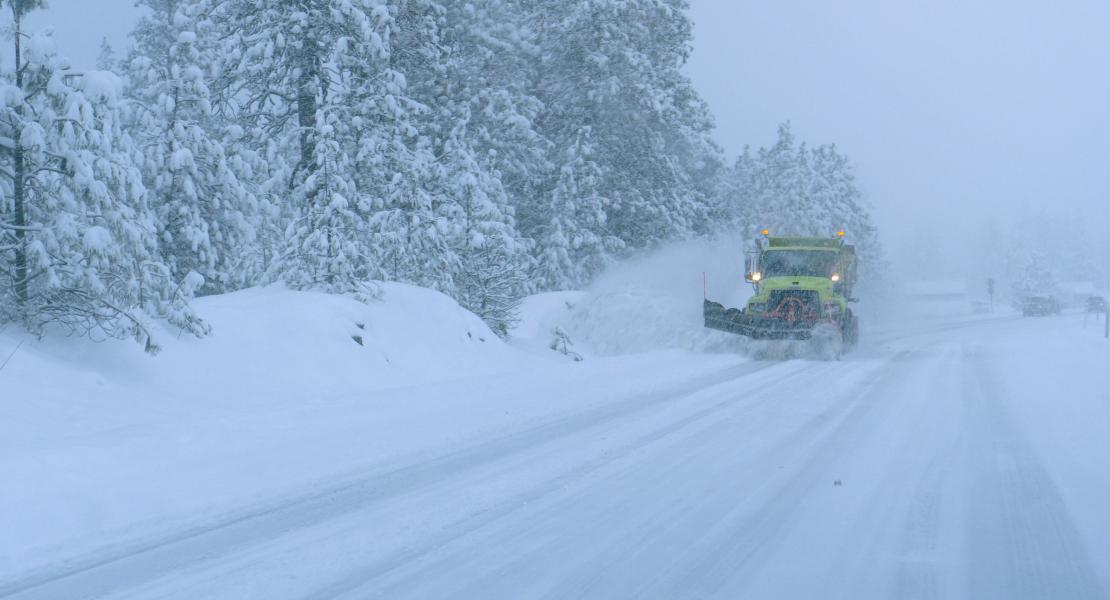 Snow plow driving down a snow covered road