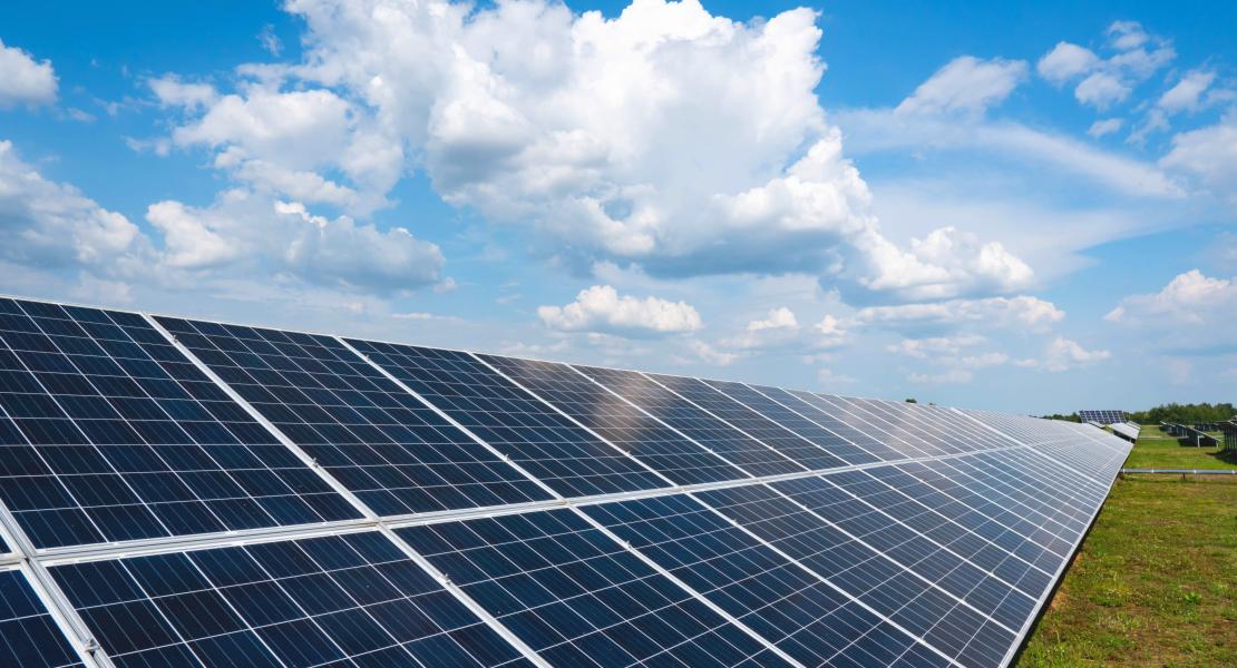 Solar Panels in field with blue skies and white fluffy clouds behind them